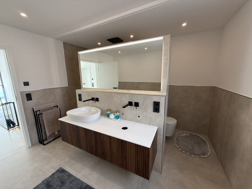 Modernes Bad in Beige mit Holzwaschtisch und großem Spiegel