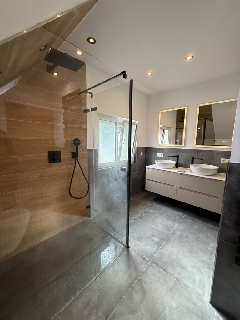 Bad mit Holzoptikfliesen in der Dusche und grauen Bodenfliesen