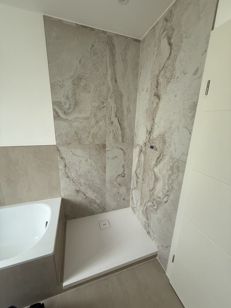 Dusche mit großformatigen Fliesen in lebendiger Natursteinoptik