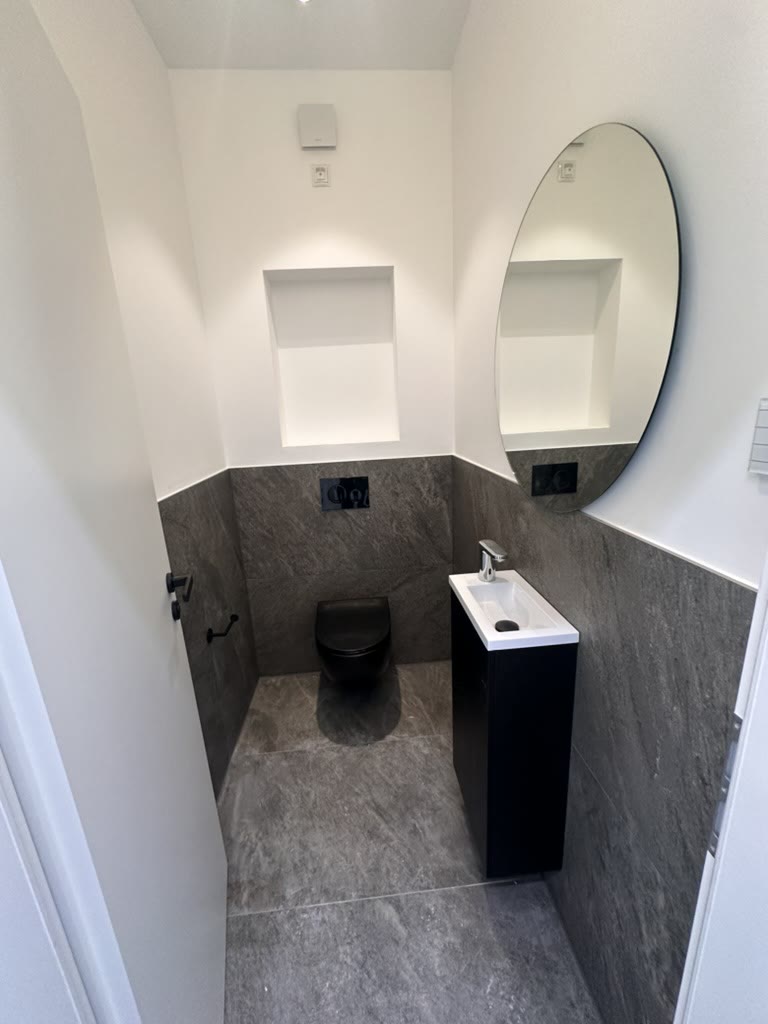 Gäste-WC mit dunklen Steinoptikfliesen und schwarzer Keramik