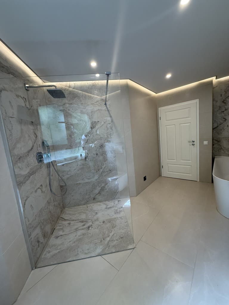 Walk-in-Dusche mit großformatiger Marmoroptik und indirektem Licht
